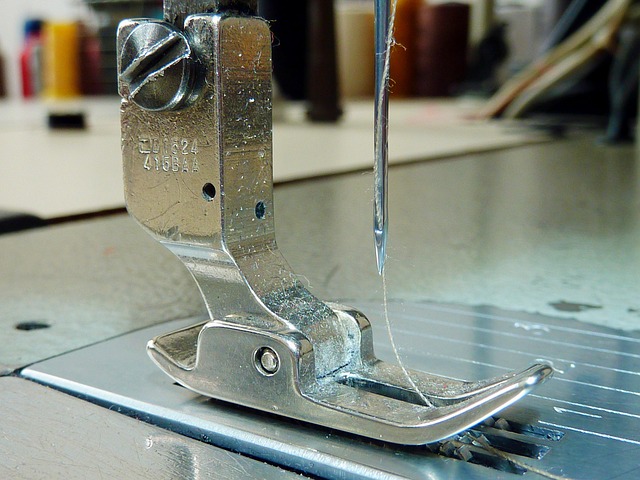 close-up sewing machine presser foot needle plate and fabric under soft workshop lighting